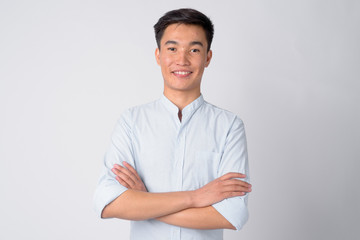 Portrait of young happy Asian businessman smiling with arms crossed
