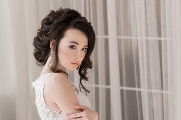 Portrait of a beautiful bride. Wedding hairstyle and makeup. A piercing look. A look over your shoulder.