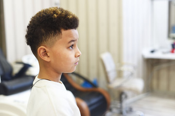 Cool stylish fashion mixed boy  in hair salon studio. Fashion kids. Curly hair african american boy close up portrait.