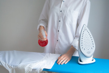 Female ironing white shirts, cleaning service, housewife.