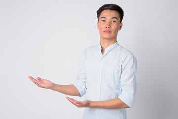 Portrait of young handsome Asian businessman showing something