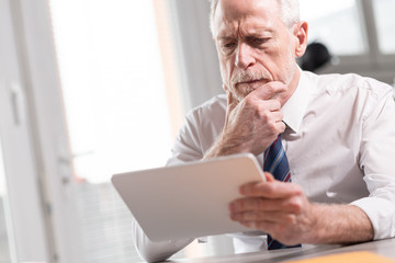 Naklejka premium Portrait of senior businessman working on tablet