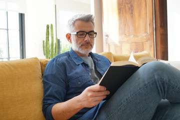 Man in 40s reading book in modern home