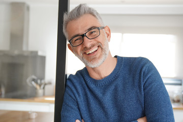 Man leaning and smiling at home in modern kitchen