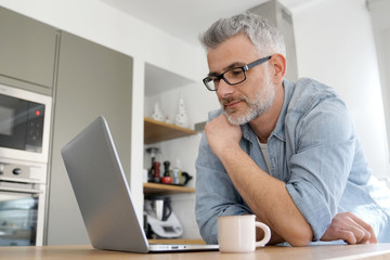 Man with computer at home in modern kitchen