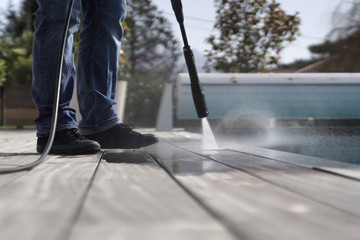 Man using high pressure washer cleaning deck