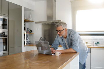 Man with computer at home in modern kitchen