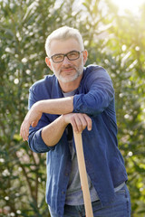 Man leaning on rake in sunny garden
