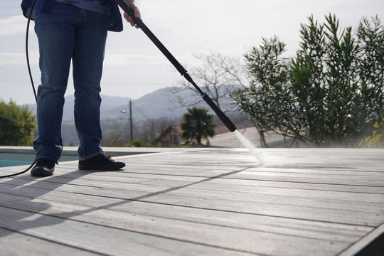 Man Using High Pressure Washer Cleaning Deck