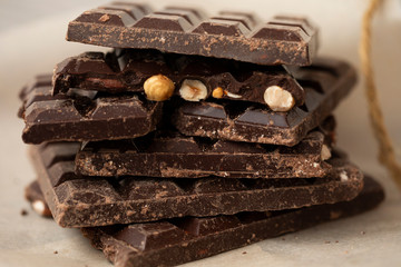 Hazelnut and almond milk and dark chocolate pieces tower. Chocolate bars on table with chocolate tower. Chocolate and nuts and choco swirl