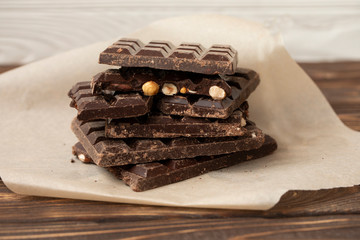 Hazelnut and almond milk and dark chocolate pieces tower. Chocolate bars on table with chocolate tower. Chocolate and nuts and choco swirl