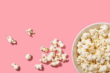 A bowl full of popcorn on pinl background with copy space.