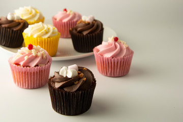 Colorful cupcakes on a white background. Pink, yellow and chocolate cupcakes. Party food. Sweet dessert or breakfast. Party, birthday food. Bright food photo. Copy space.