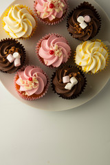 Colorful cupcakes on a white background. Pink, yellow and chocolate cupcakes. Party food. Sweet dessert or breakfast. Party, birthday food. Bright food photo. Copy space.
