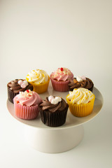 Colorful cupcakes on a white background. Pink, yellow and chocolate cupcakes. Party food. Sweet dessert or breakfast. Party, birthday food. Bright food photo. Copy space.
