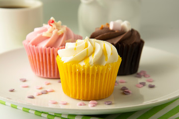 Colorful cupcakes on a white background. Pink, yellow and chocolate cupcakes. Party food. Sweet dessert or breakfast. Party, birthday food. Bright food photo.