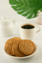 Oat Cookies and coffee breakfast, or coffee break. Oatmeal healthy biscuits. Green monstera, plam leaves. Copy space. Bright background. Food.