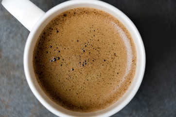 Closeup of coffee foam.Coffee in white cup,top view