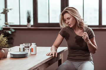 Blonde-haired stressed woman sweating and having wet t-shirt