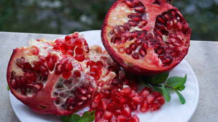 Pieces of half pomegranate apple. Delicious juicy pomegranate seeds or grains closeup. Organic nutrition, healthy lifestyle, clean eating and diet concept.  Agricultural end products background photo.