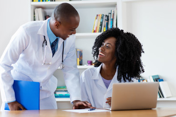 African american chief physician with young female doctor at work