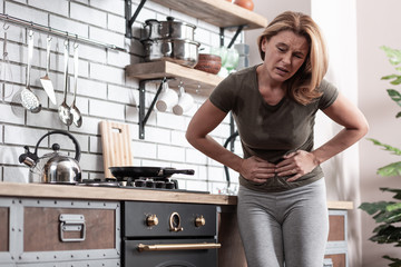Woman wearing t-shirt having strong and immediate stomachache