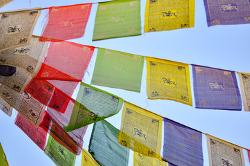 Low angle view of colorful Buddhist flags on a pole with the mantra written all over. 
