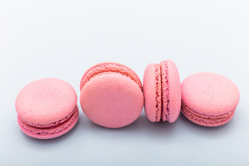 French pink macaroons cookies in rows on a light blue background