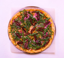 Flat lay pizza with arugula, beef and baked tomatoes on the wooden board on white background