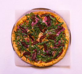 Flat lay pizza with arugula, beef and baked tomatoes on the wooden board on white background
