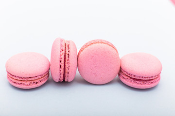 French pink macaroons cookies in rows on a light blue background