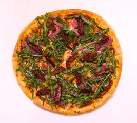 Flat lay pizza with arugula, beef and baked tomatoes on the wooden board on white background
