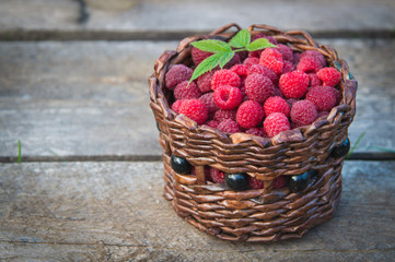 ripe raspberries in a basket on a wooden background