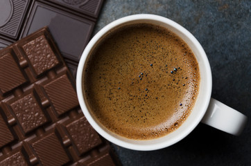 Closeup of tasty coffee with pieces of chocolate on grey table