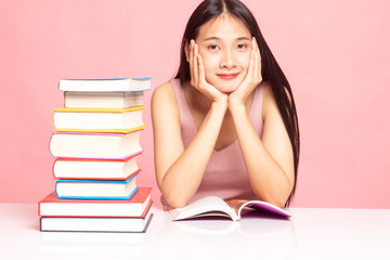 Young Asian woman read a book with books on table.