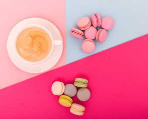 Fototapeta na wymiar Cup of coffee with macaron on color background from above, flat lay