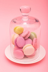 Many macaroons in a glass vase isolated on pink background