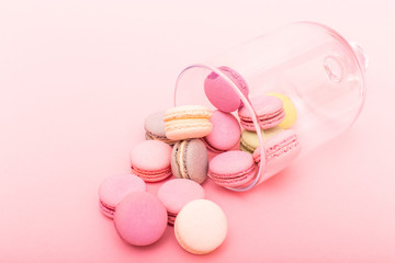 Many macaroons in a glass vase isolated on pink background