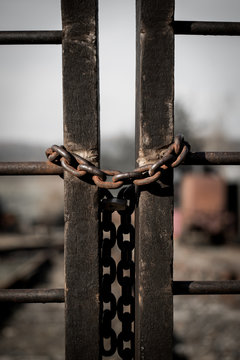 Rusty old padlock with an iron chain at a fence