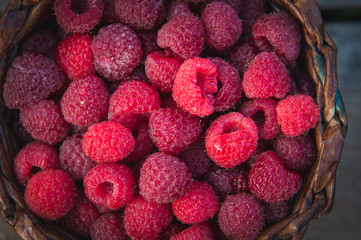 ripe raspberries in a basket on a wooden background