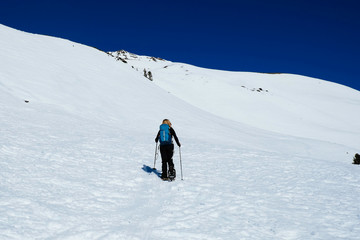 Fototapeta na wymiar A woman is snowshoeing uphill in the italian alps /Vinschgau/ Tirol