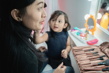Obraz premium happy mother and kid playing with make up looking at mirror