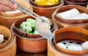 Closeup. selective focus of  chopsticks picking up of dumpling. Dim sum set in the bamboo basket