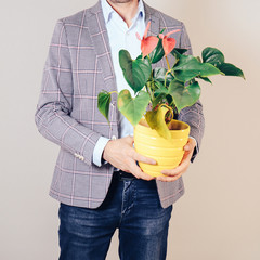 A man holding a pot with a flower in his hands. The concept of gift, surprise, delivery.