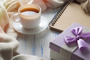 Coffee cup, notebook, gift on a white wooden table. Concept of Spring