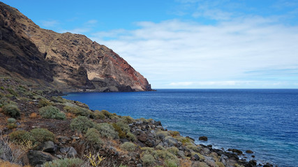 Fototapeta na wymiar Solitary landscape of the wild south coast of the island of El Hierro, with endemic tropical flora growing on the rocky soil, abrupt volcanic cliffs and blue Atlantic Ocean, Canary Islands, Spain