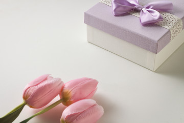 Three Pink Tulips and a Gift Box On The White Background. Artificial flowers. Copy space