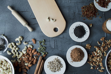 woman is making homemade sweets from nuts and dried fruits without sugar. top view with hands on black concrete background