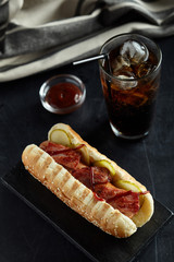 Hot dog with glass of coke on black background
