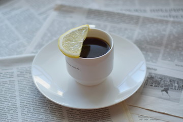 cup of coffee jn the white plate with slice of lemon